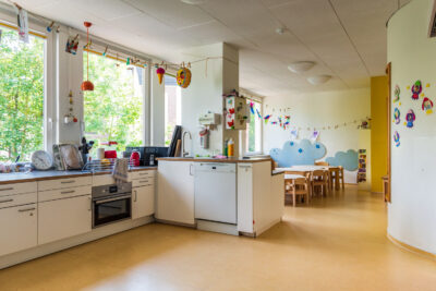 Blick auf Küche und Tische im Spielbereich der Familiengruppe