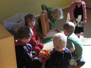 Kinder sitzen auf dem Fussboden und spielen