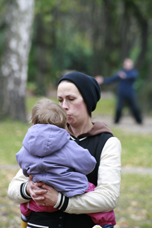 Catrin Luther trägt ein Kind. Im Hintergrund macht jemand Tai-Tchie